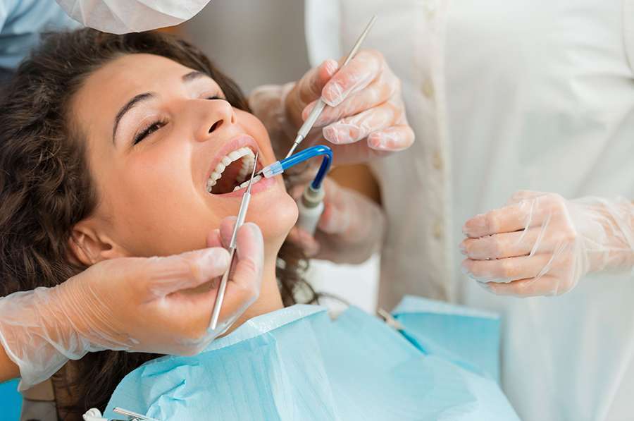 Woman having tooth extracted by dentist. Dentist using dental instruments.